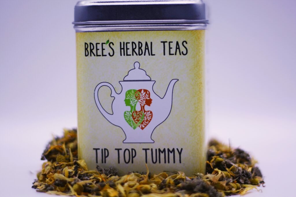 Digestive herbal tea blend in a yellow tin with herbs surrounding it and a white background