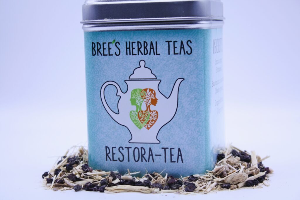 Immune boosting Herbal tea in a tin surrounded by loose herbs with a white background