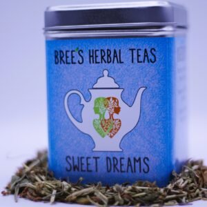 Sweet Dreams sleep tea in a blue tin with herbs around it and a white background