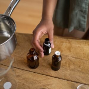 a person about to pick up a brown glass bottle on the wooden surface